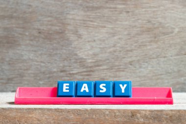 Tile letter on red rack in word easy on wood background