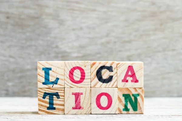 Letter block in word location on wood background