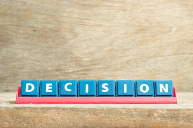Tile letter on red rack in word decision on wood background