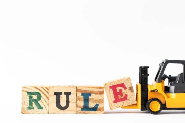 Toy forklift hold wood letter block e to complete word rule on white background — Stock Photo, Image