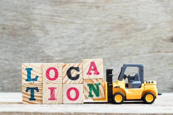 Toy forklift hold letter block a n untuk melengkapi lokasi kata pada latar belakang kayu — Stok Foto