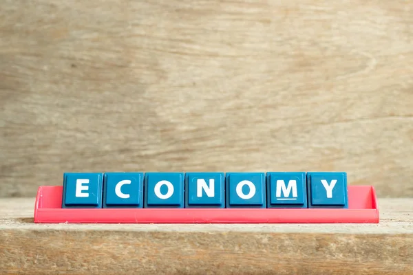 Dlaždice dopis na červeném stojanu ve slově ekonomie na pozadí dřeva — Stock fotografie