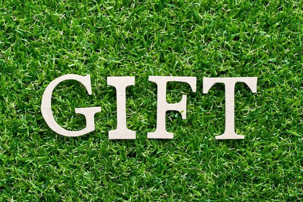 Alfabeto de madera en regalo de palabra sobre fondo de hierba verde artificial —  Fotos de Stock