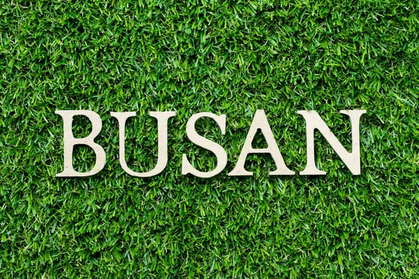 Alfabeto de madeira letra na palavra Busan no fundo grama verde — Fotografia de Stock