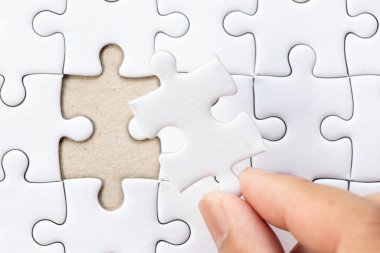 Arka plan beyaz düz jigsaw maç veya yerine getirmek için eksik parçası tutan el ile kapalı