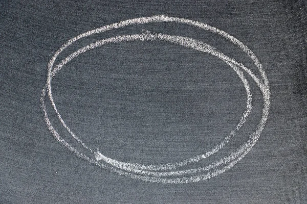 Beyaz renkli tebeşirle çizilen el veya siyah tahta arka planda oval şekil