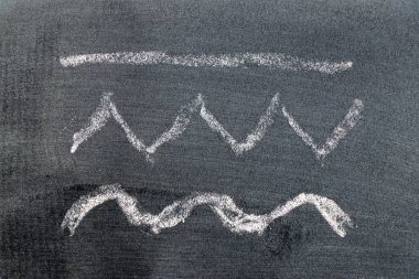 White color chalk hand drawing in set of line, zigzag and wavy shape on black board 
