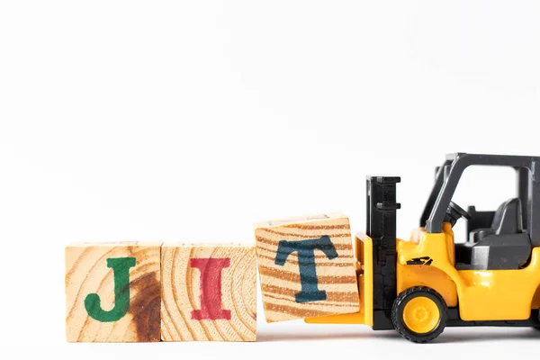 おもちゃフォークリフトは白い背景の単語Jit (Just in time)を完了するために木の手紙のブロックTを保持します — ストック写真