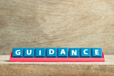 Ahşap arka planda kelime rehberliğinde kırmızı raftaki döşeme harfi