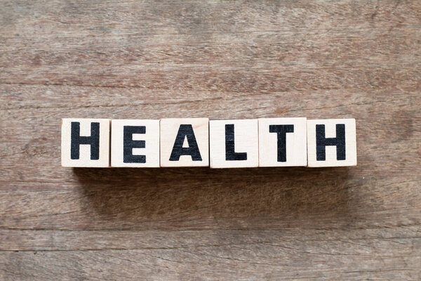 Буква блок в здоровье слова на деревянном фоне
