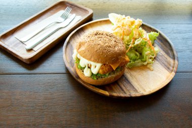Ahşap tabakta sebze salatalı kızarmış balık fileto burger.