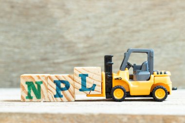 Toy forklift harf engeli l, tahta arkaplan üzerinde NPL sözcüğünü tamamlamak için (Performans Kredisi Olmayan Edebiyatın kısaltması, Patent Olmayan Edebiyat)