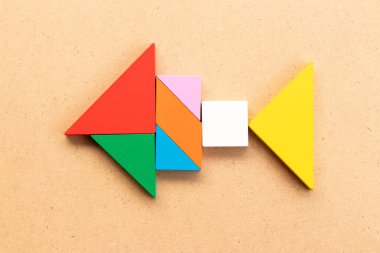 Ahşap arka planda balık şeklinde renkli tangram yapbozu