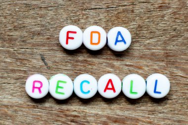 White bead with color letter in word fda recall on wood  background clipart