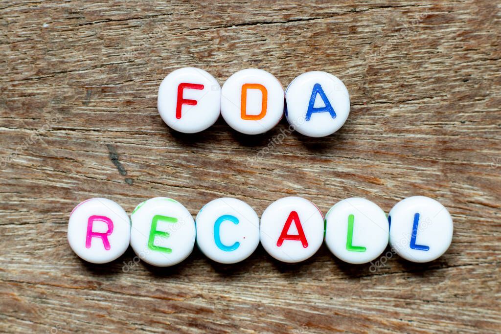 White bead with color letter in word fda recall on wood  background