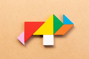 Ahşap arka planda gergedan şeklinde renkli tangram yapbozu