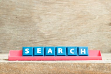 Ahşap arkaplanda kelime aramasında kırmızı raftaki döşeme harfi