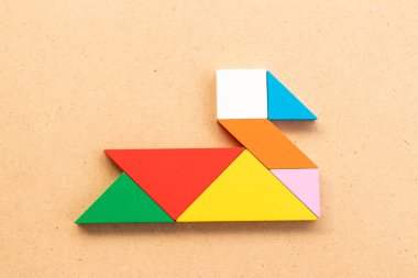 Kuğu şeklinde renkli tangram yapbozu veya ahşap arka planda ördek şekli