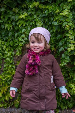 Sevimli küçük kız çocuğu ile yabani üzüm güneşli bir duvarının yakınında oynama ve keyfi mutluluk sonbahar günü ayakta