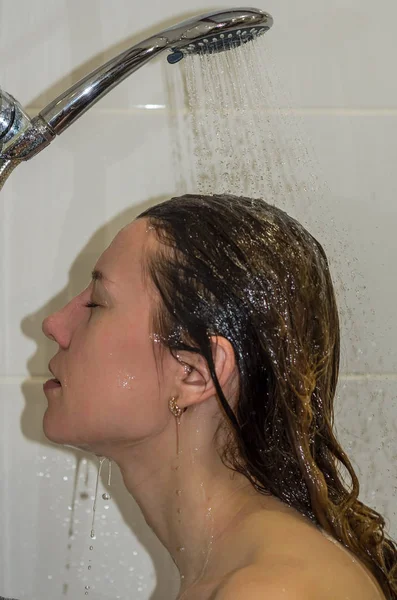 Jeune belle fille aux cheveux longs, nue, prenant une douche et se lavant la tête — Photo