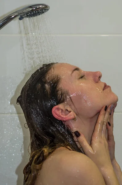 Молодая красивая девушка с длинными волосами, голая, принимает душ и моет голову — стоковое фото