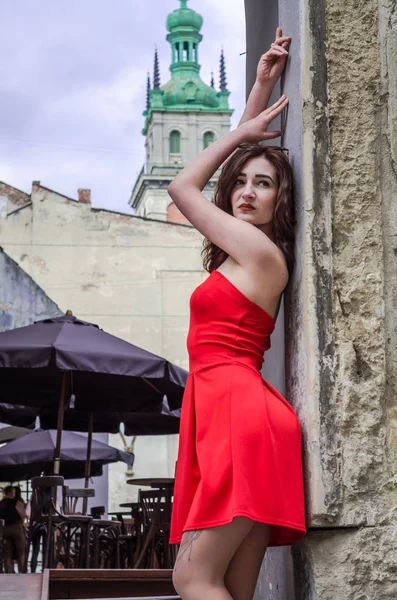年轻漂亮的女孩，穿着红色漫步的利沃夫市古老的街道 — 图库照片