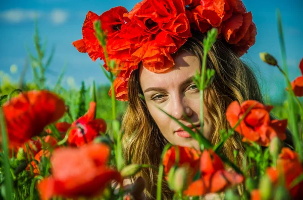 Portrait of a young beautiful girl in a poppy field with a wreath of poppies on her head on a hot summer sunny day — Stock Photo, Image