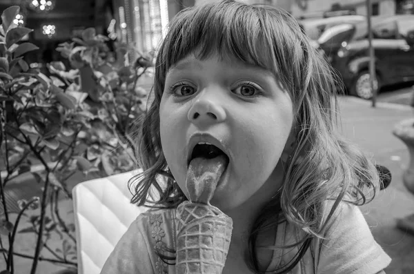 Piccola ragazza affascinante il bambino mangia e lecca le lingue del gelato in un caffè di strada a Roma, la capitale d'Italia — Foto Stock