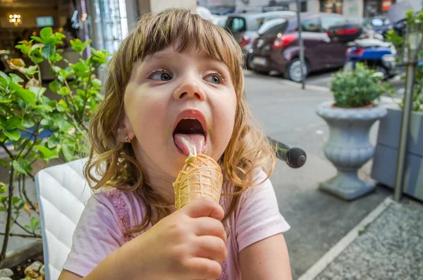 Piccola ragazza affascinante il bambino mangia e lecca le lingue del gelato in un caffè di strada a Roma, la capitale d'Italia — Foto Stock