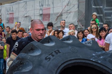 Lviv, Ukrayna - Ağustos 2017: Süper güçlü bir atlet yarışmalar Strongmen maçında coşkulu seyirci önünde büyük iyi yıl direksiyonda yükseltir