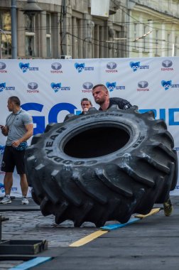 Lviv, Ukrayna - Ağustos 2017: Süper güçlü bir atlet yarışmalar Strongmen maçında coşkulu seyirci önünde büyük iyi yıl direksiyonda yükseltir