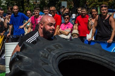 Lviv, Ukrayna - Ağustos 2017: Süper güçlü bir atlet yarışmalar Strongmen maçında coşkulu seyirci önünde büyük iyi yıl direksiyonda yükseltir