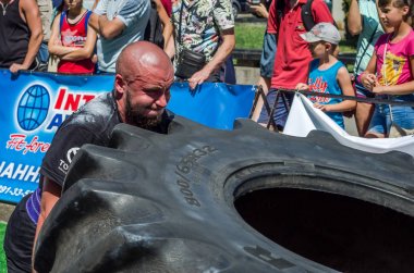 Lviv, Ukrayna - Ağustos 2017: Süper güçlü bir atlet yarışmalar Strongmen maçında coşkulu seyirci önünde büyük iyi yıl direksiyonda yükseltir