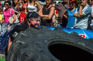 Lviv, Ukrayna - Ağustos 2017: Süper güçlü bir atlet yarışmalar Strongmen maçında coşkulu seyirci önünde büyük iyi yıl direksiyonda yükseltir