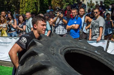 Lviv, Ukrayna - Ağustos 2017: Süper güçlü bir atlet yarışmalar Strongmen maçında coşkulu seyirci önünde büyük iyi yıl direksiyonda yükseltir