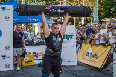 Lviv, Ukrayna - Ağustos 2017: Güçlü bir atlet hayran Strongmen Oyunları'nda seyirci önünde başını halter bir büyük ağır toparlayabiliriz alır