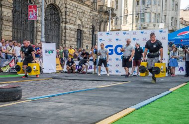 Lviv, Ukrayna - Ağustos 2017: Güçlü vücut geliştirmeci atlet güçlü adam oyunun coşkulu seyirci önünde büyük bir çelik ağır kanala asansörleri