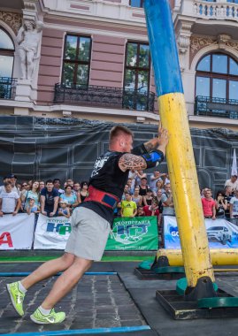 Lviv, Ukrayna - Ağustos 2017: Güçlü vücut geliştirmeci atlet güçlü adam oyunun coşkulu seyirci önünde büyük bir çelik ağır kanala asansörleri