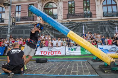 Lviv, Ukrayna - Ağustos 2017: Güçlü vücut geliştirmeci atlet güçlü adam oyunun coşkulu seyirci önünde büyük bir çelik ağır kanala asansörleri