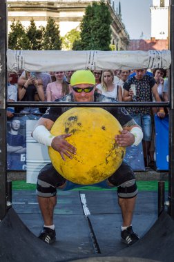 Lviv, Ukrayna - Ağustos 2017: Güçlü atlet bir vücut geliştirmeci Strongmen oyunlarda büyük bir ağır taş sarı topun asansörleri
