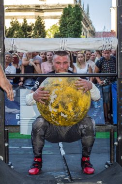 Lviv, Ukrayna - Ağustos 2017: Güçlü atlet bir vücut geliştirmeci Strongmen oyunlarda büyük bir ağır taş sarı topun asansörleri