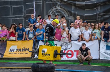 Lviv, Ukrayna - Ağustos 2017: Güçlü atlet bir vücut geliştirmeci egzersiz ağır demir bavul bir çiftçinin yürüyüş, coşkulu seyirci önünde strongmen oyun taşır