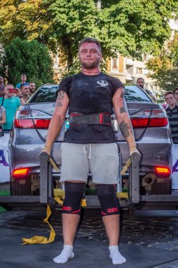 Lviv, Ukrayna - Ağustos 2017: Güçlü atlet vücut geliştirmeci Strongmen maçta coşkulu seyirci önünde Toyota otomobil asansörleri