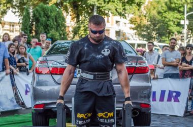 Lviv, Ukrayna - Ağustos 2017: Güçlü atlet vücut geliştirmeci Strongmen maçta coşkulu seyirci önünde Toyota otomobil asansörleri
