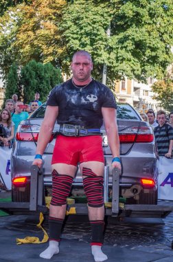 Lviv, Ukrayna - Ağustos 2017: Güçlü atlet vücut geliştirmeci Strongmen maçta coşkulu seyirci önünde Toyota otomobil asansörleri