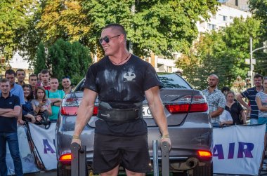 Lviv, Ukrayna - Ağustos 2017: Güçlü atlet vücut geliştirmeci Strongmen maçta coşkulu seyirci önünde Toyota otomobil asansörleri