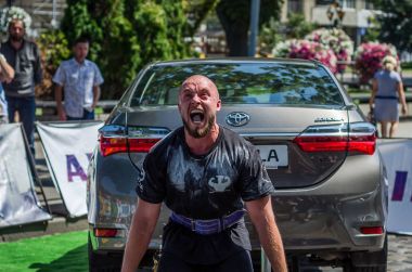 Lviv, Ukrayna - Ağustos 2017: Güçlü atlet vücut geliştirmeci Strongmen maçta coşkulu seyirci önünde Toyota otomobil asansörleri