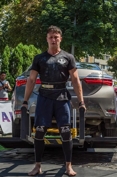 Lviv, Ukrayna - Ağustos 2017: Güçlü atlet vücut geliştirmeci Strongmen maçta coşkulu seyirci önünde Toyota otomobil asansörleri