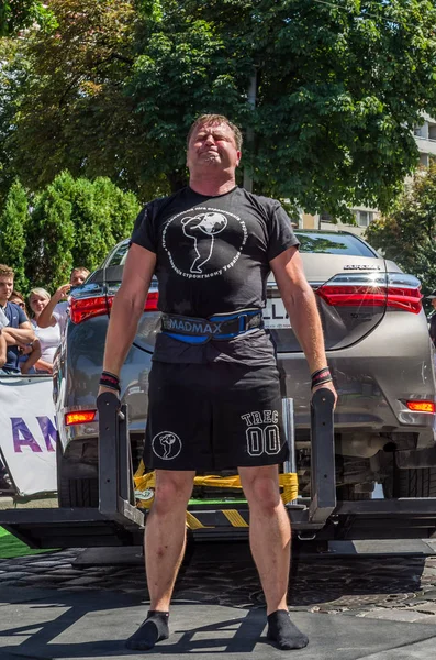 Lviv, Ukrayna - Ağustos 2017: Güçlü atlet vücut geliştirmeci Strongmen maçta coşkulu seyirci önünde Toyota otomobil asansörleri