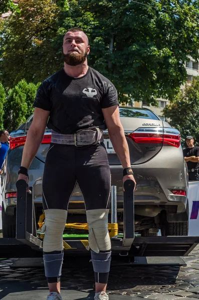 Lviv, Ukrayna - Ağustos 2017: Güçlü atlet vücut geliştirmeci Strongmen maçta coşkulu seyirci önünde Toyota otomobil asansörleri